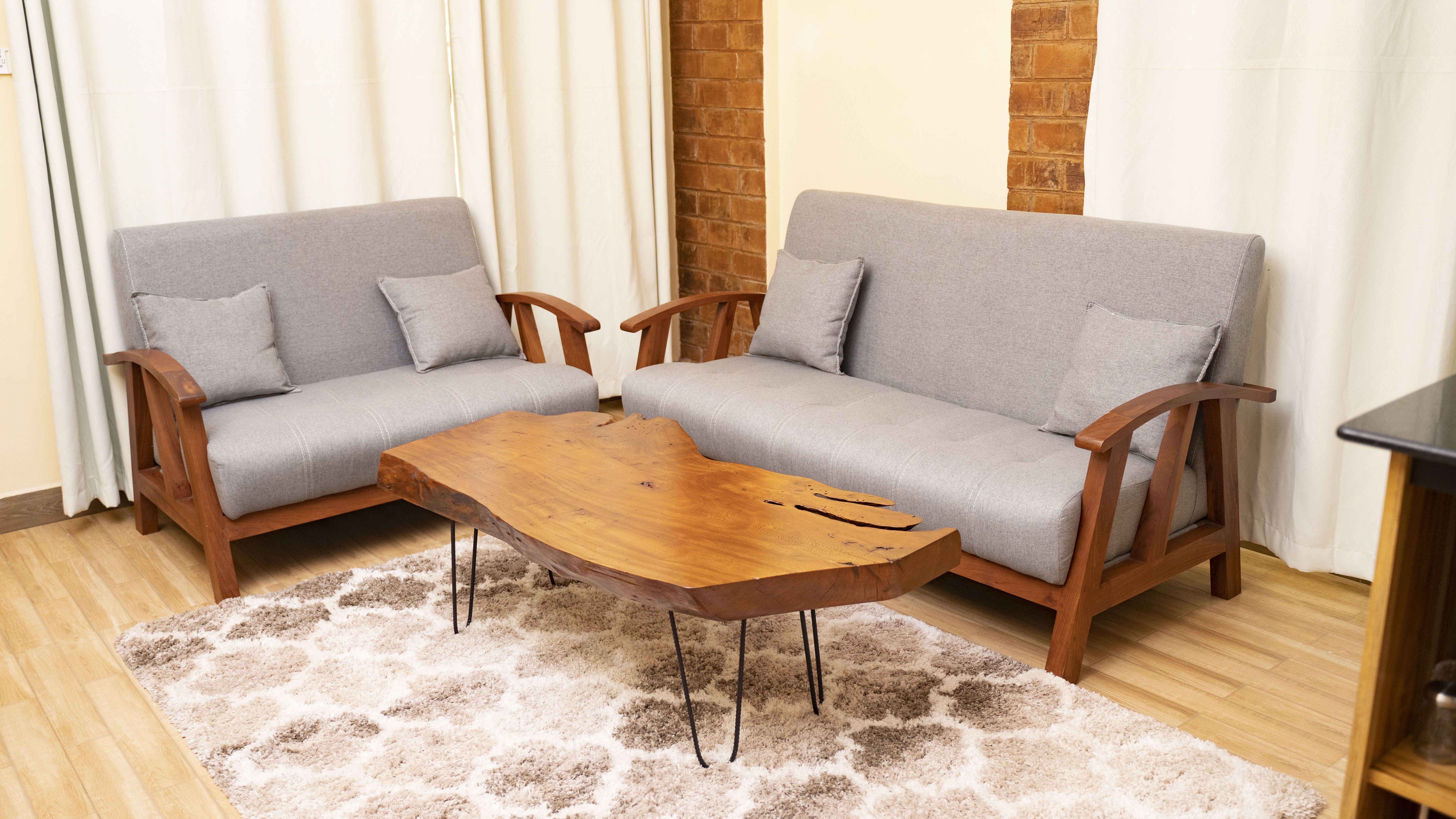 Sitting room — mninga-frame sofas around a live-edge coffee table, opening into the kitchen beyond