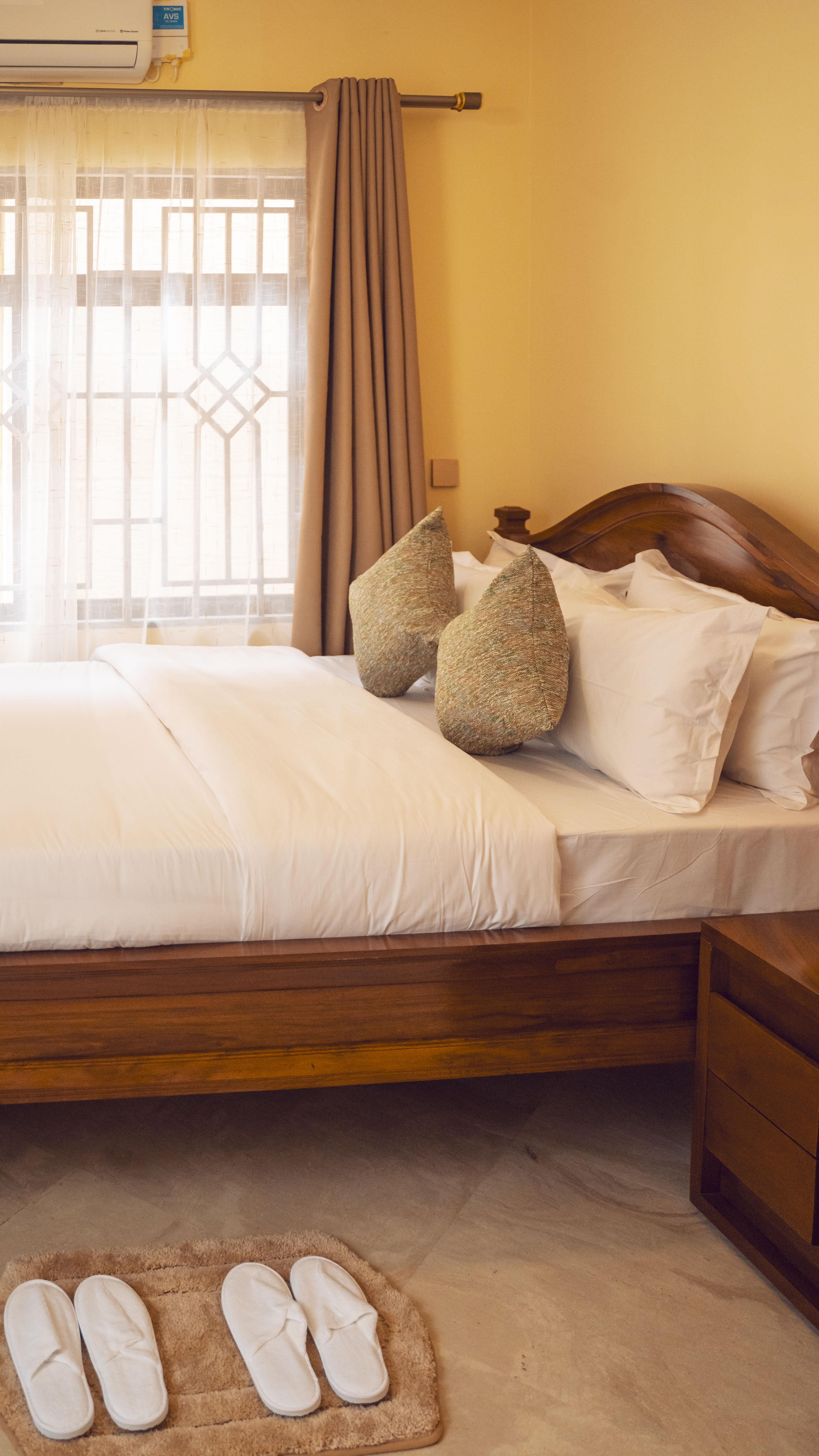 Master bedroom — hand-carved mninga headboard, Egyptian-cotton linens and guest slippers on a bath mat